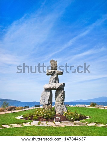 Inukshuk, symbol of the 2010 winter olympic games, with blue sky at English Bay in Vancouver, British Columbia, Canada