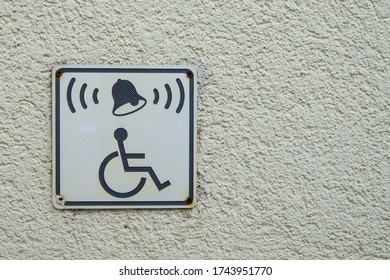 Invalid On Wheelchair And Ring Bell Sign On The Wall. Disabled People Help With Copy Space For Text