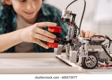 Inventive teen kid constructing robot in the studio