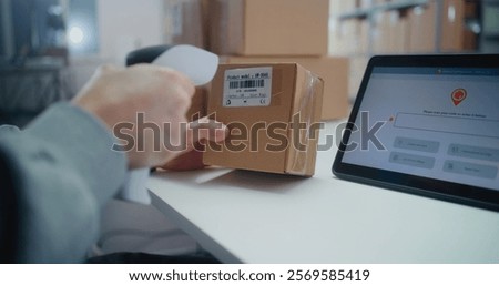 Inventory Manager Scans Code on Cardboard Box with Barcode Scanner, Checks Parcel Information. Tablet Computer Screen Shows Delivery Tracking System for Monitoring Package with Online Orders. Close Up