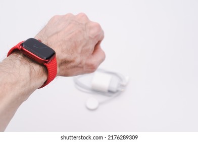 INVERIGO, ITALY - Nov 20, 2021: Man Wrist Wearing Apple Watch Product Red And Charger On A White Tabletop With Text Space