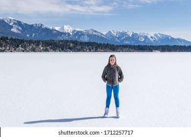 INVERMERE, CANADA - MARCH 17, 2020: girl on frozen Windermere lake and rocky mountains in british columbia canada.