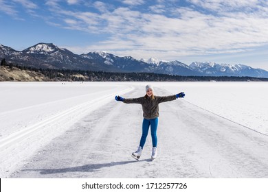INVERMERE, CANADA - MARCH 17, 2020: girl on frozen Windermere lake and rocky mountains in british columbia canada.