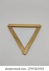 Inverted equilateral triangle shape made from natural wooden slats isolated on white background. Minimalist geometric frame.