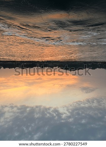 Inverted perspective of a dramatic sunset over a river with dark water and orange sky