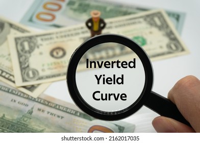 Inverted Yield Curve.Magnifying glass showing the words.Background of banknotes and coins.basic concepts of finance.Business theme.Financial terms. - Shutterstock ID 2162017035