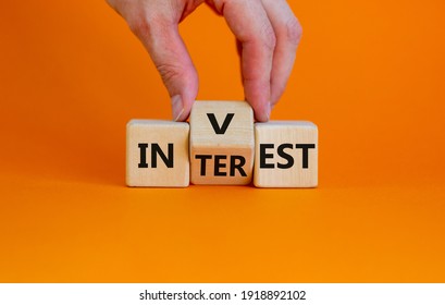 Invest or interest symbol. Businessman turns a wooden cube and changes the word 'invest' to 'interest'. Beautiful orange background, copy space. Business and invest or interest concept. - Shutterstock ID 1918892102