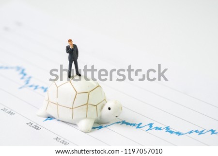 Invest with slow but steady for long term success metaphor, miniature people businessman riding turtle or tortoise walking on rising growth stock market value graph, value investment concept.
