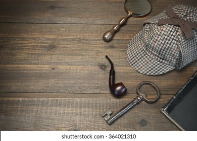 Investigation Concept. Private Detective Tools On The Wood Table Background. Deerstalker Cap, Old Key  And Book, Tobacco  Pipe, Vintage Magnifying Glass. Overhead View