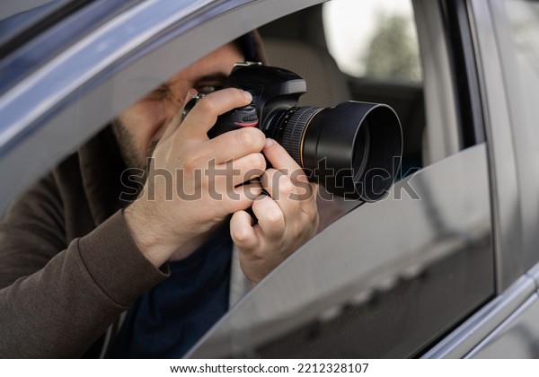 Investigator or private detective, reporter or
paparazzi sitting in car and taking photo with professional camera,
close up
