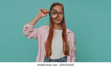 Investigator researcher scientist girl holding magnifying glass near face, looking into camera with big zoomed funny eye, searching, analysing. Young child kid on blue studio wall background indoors - Shutterstock ID 2201761635