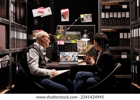 Investigators explaining crime scene evidence to criminology team during online videocall meeting conference. Private detectives working late at night at criminal case in arhive room Foto stock © 