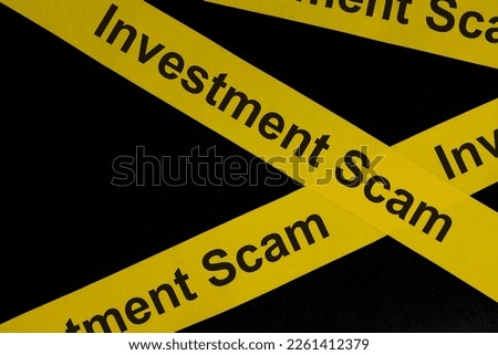 Investment scam and fraud alert, caution and warning concept. Yellow barricade tape with word in dark black background.