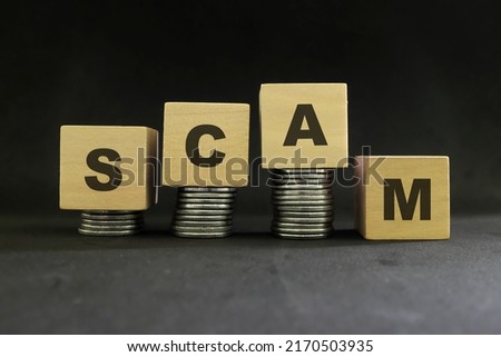 Investment scam, fraud and Ponzi scheme concept. Stack of coins on wooden blocks with word scam in dark black background.
