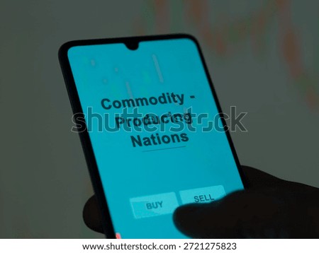 An investor analyzing the commodity - producing nations etf fund on a screen. A phone shows the prices of Commodity - Producing Nations