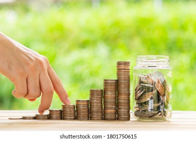 Investor business man finger walking on row of coins stack with blur green nature background. Money saving concept or Business growth concept.