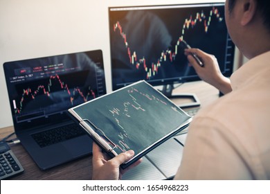 Anleger analysieren die Grafik der Börse mit einem Stift, der auf den Computerbildschirm zeigt.