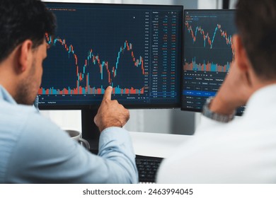 Investor stock trading with serious face sharing with coworker while drinking coffee by using smartphone and pc to show dynamic database of trend graph. Monitor showing investment exchange. Sellable. - Powered by Shutterstock