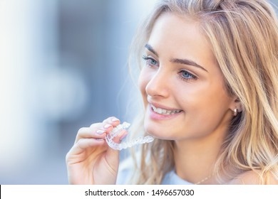 Invisalign Orthodontics Concept - Young Attractive Woman Holding - Using Invisible Braces Or Trainer.