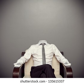 invisible man in formal wear sitting on armchair against grey background