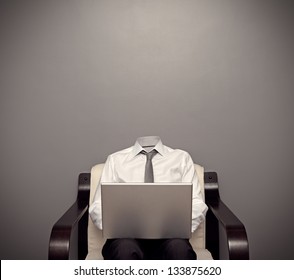 invisible man in formal wear sitting on chair and working with laptop against grey background
