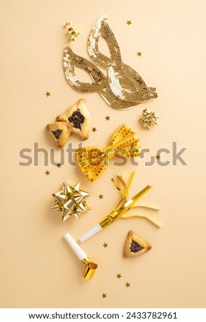 Invitation concept for a lavish Purim event with top view vertical photo of triangular pastries, and opulent gold items such as masks, blowers and confetti on beige canvas, space reserved for wording
