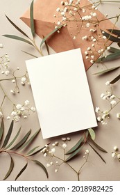 Invitation or greeting card mockup with craft paper envelope, eucalyptus and gypsophila twigs. Card mockup with copy space on beige background. - Shutterstock ID 2018982425