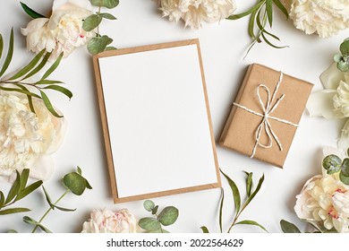 Invitation or greeting card mockup with envelope, gift box and white peony flowers and eucalyptus twigs - Shutterstock ID 2022564629