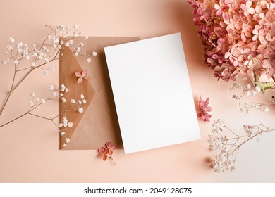 Invitation or greeting card mockup with envelope and hydrangea and gypsophila flowers decorations.