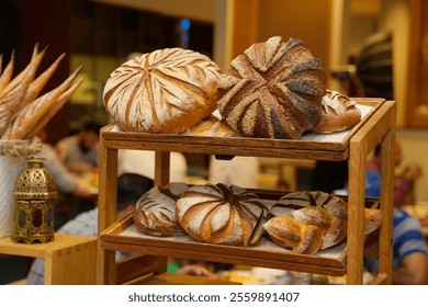 An inviting array of artisan breads, including beautifully crafted loaves and rolls, presented on a rustic wooden rack, surrounded by the warm ambiance of a bustling bakery