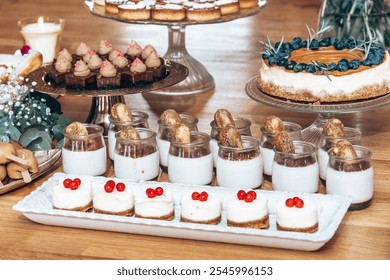 An inviting assortment of desserts including panna cotta in jars, mini cheesecakes topped with red currants, rich chocolate bites, and a blueberry-topped cheesecake, arranged elegantly on a wooden tab - Powered by Shutterstock