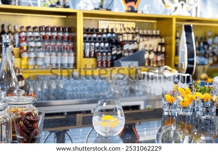 An inviting bar setup featuring a wide selection of spirits and garnishes, with a freshly prepared gin and tonic waiting to be served.