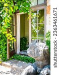 Inviting entry with door open with grape vine and green vines growing up the outside of a Winery Vineyard building with stone statue 