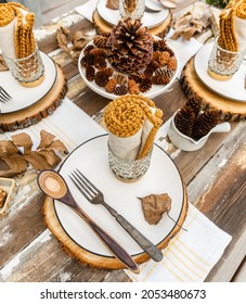 An Inviting Fall Table Setting On A Distressed Barn Wood Farmhouse Table With A Pinecone Centerpiece And Mustard Colored Rolled Linen Napkins. Unique Wooden Spoons Add Warmth. 