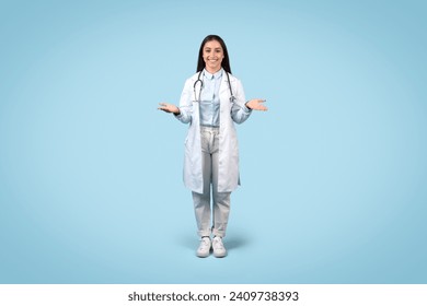 Inviting female doctor with friendly smile, open hands gesture, dressed in lab coat and casual wear against calming blue background, full body view - Powered by Shutterstock