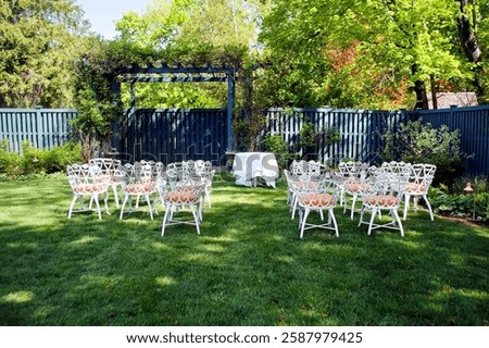 An inviting garden setting features white chairs arranged around a central table under a blue trellis.