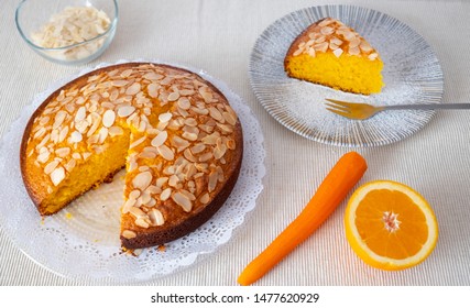 Inviting homemade carrot cake freshly baked with orange and almonds. One piece ready to eat. Clear background and orange color