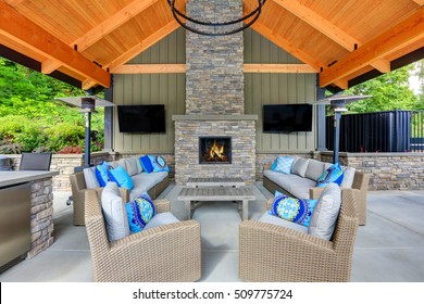 Inviting Interior Of Covered Patio Area  In Tacoma Lawn Tennis Club. Stone Fireplace, Wicker Furniture With Beige Cushions And Bright Blue Pillows. Northwest, USA