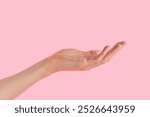 An inviting open hand against a soft pink backdrop offering a sense of calm and connection in a minimalist setting