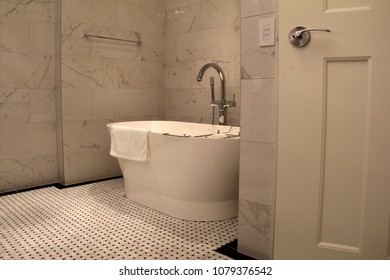 Inviting Stand Alone Tub In Bathroom With Tiled Floors And Walls In Warm Earth-tone Colors.