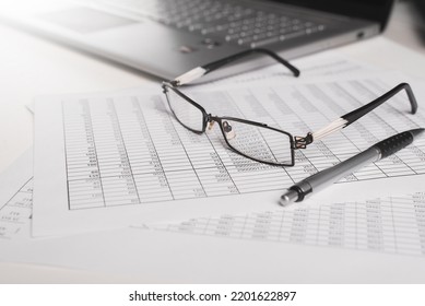 Invoices, Accounting Documents, Pen, Laptop And Eyeglasses At The Workplace In The Office. Balance, Budget, Business And Finance Concept. Close-up, Low Angle View, Selective Focus.