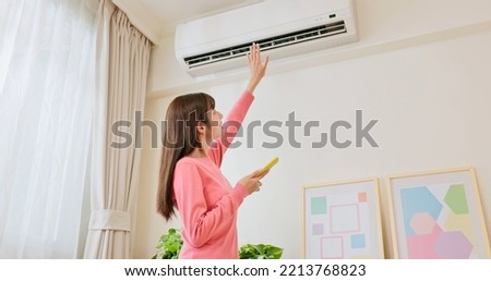 IOT smart home concept - asian woman using mobile phone to turn on air conditioner or heater
