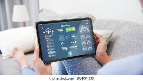 Iot Smart Home Concept - Rear View Of Asian Woman Ask Digital Tablet To Set Temperature Of Air Conditioner More Higher By Voice At Home And All The Electric Meter In House Getting Energy-efficient