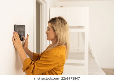 Iot Smart Home Concept - rear view of asian woman ask digital tablet to set temperature of air conditioner more higher by voice at home and all the electric meter in house getting energy-efficient. - Shutterstock ID 2268973847