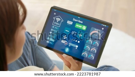 Iot Smart Home Concept - rear view of asian woman ask digital tablet to set temperature of air conditioner lower by voice at home and all the electric meter in house getting energy-efficient  ストックフォト © 