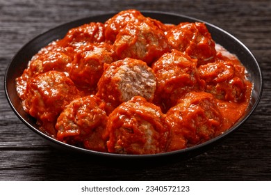 Iowa Ham Balls of ground beef, ground ham and crackers crumbs with a tomato brown sugar glaze in black bowl on dark wooden table, landscape view from above, close-up - Powered by Shutterstock