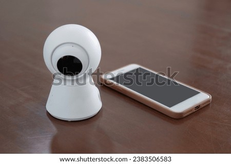 IP Camera. CCTV wireless IP security camera with 360 degrees rotating head with a smartphone on the table, Concept of home security system