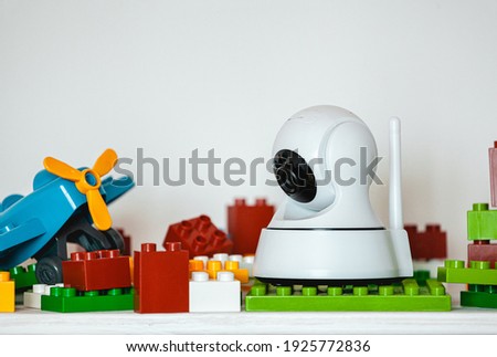 IP camera on the shelf with toys, serving as a baby monitor