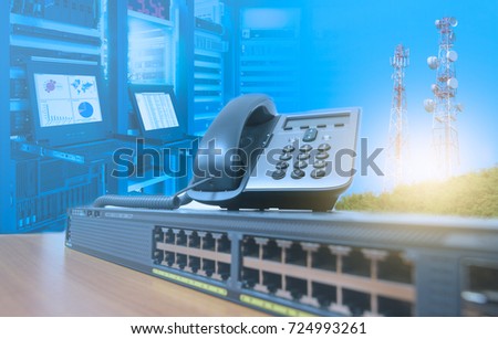 IP telephone on networking switch with blurred server rack cabinet data center room and telecommunication tower
