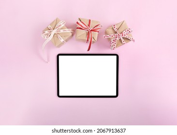 IPad Pro With White Screen On Pink Color Background With Christmas Gift. Flatlay. 